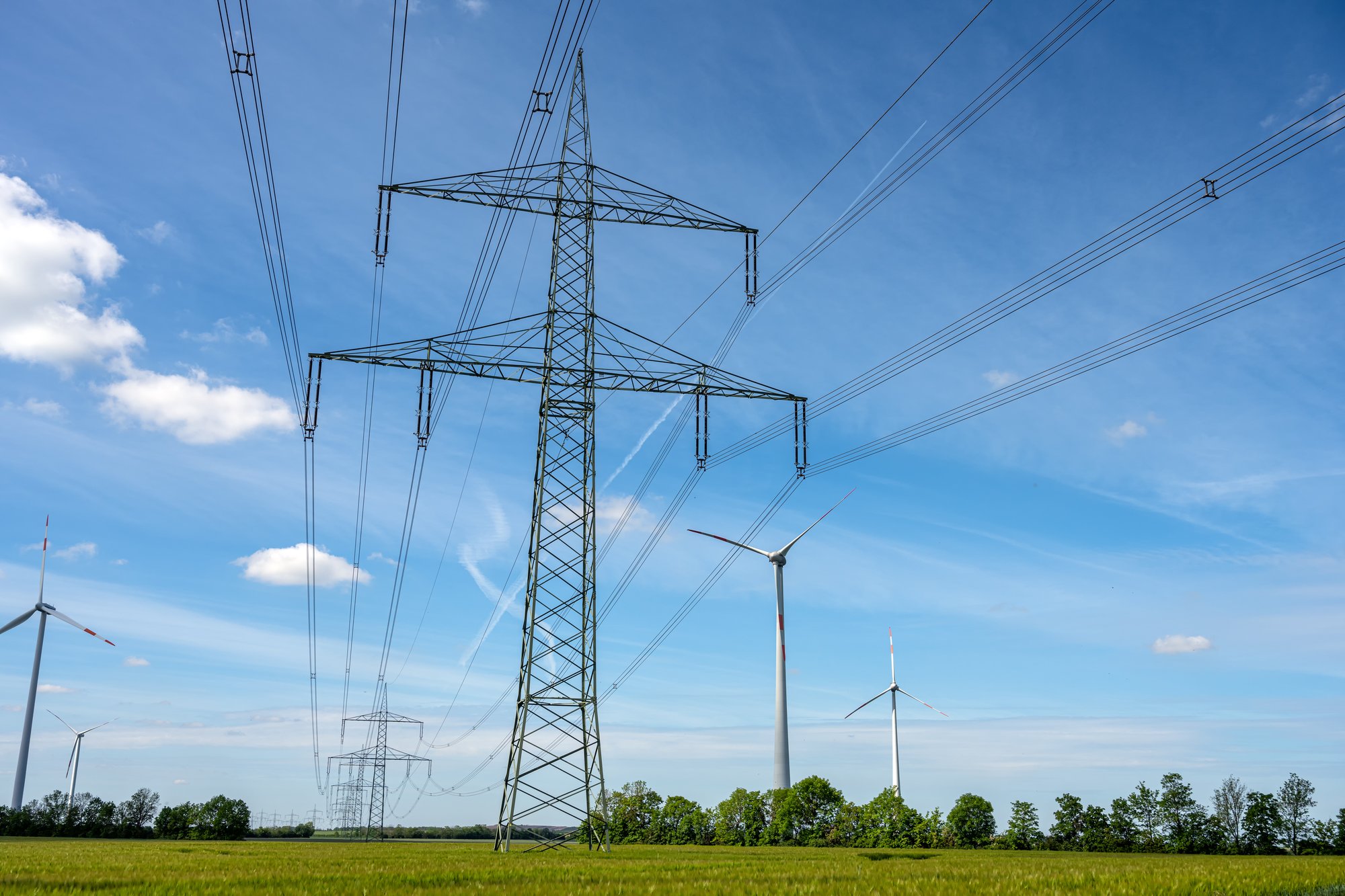 Electricity pylons and wind turbines at sunset