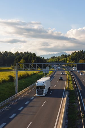 vrachtwagens-rijden-over-de-snelweg-omringd-door-velden-en-bomen-waardoor-het-vrachtvervoer-wordt-vergemakkelijkt